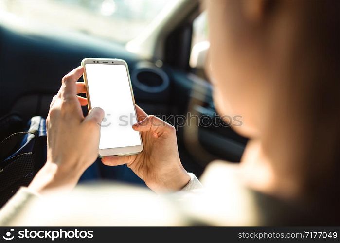 Woman is sitting in the passenger seat of a car and is watching a news feed of one of the social networks on her smartphone.. Woman is sitting in the passenger seat of a car and is watching a news feed of one of the social networks on her smartphone