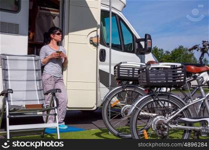 Woman is standing with a mug of coffee near the camper. Caravan car Vacation. Family vacation travel, holiday trip in motorhome