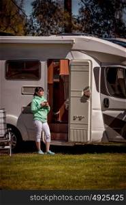Woman is standing with a mug of coffee near the camper. Caravan car Vacation. Family vacation travel, holiday trip in motorhome RV