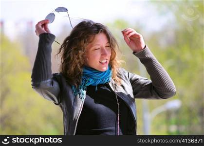 woman is taking off her sunglasses in park