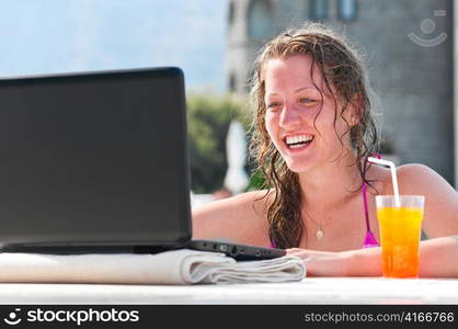 woman is using laptop from swimming pool near the hotel