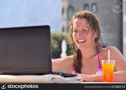 woman is using laptop from swimming pool near the hotel