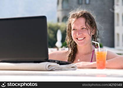 woman is using laptop from swimming pool near the hotel