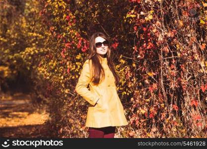 Woman is walking in autumnal park in glasses