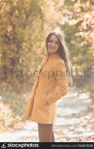 Woman is walking in autumnal park in yellow coat