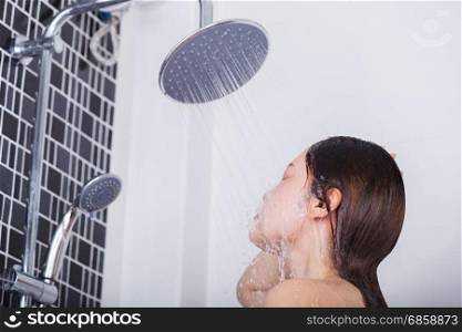 Woman is washing her face by rain shower head