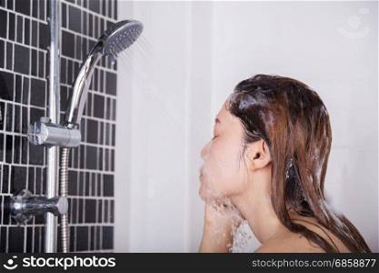 Woman is washing her face by shower head