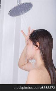 Woman is washing her hair and face by rain shower head