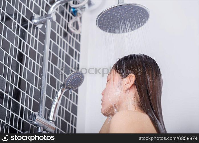 Woman is washing her hair and face by rain shower head