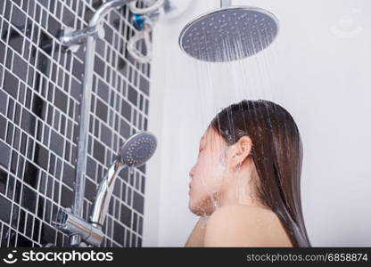 Woman is washing her hair and face by rain shower head