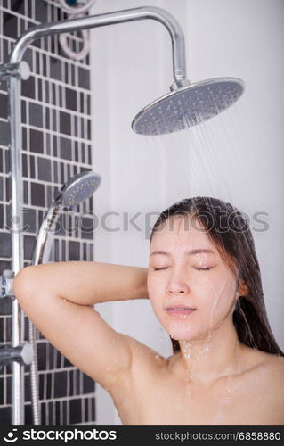 Woman is washing her hair and face by rain shower head