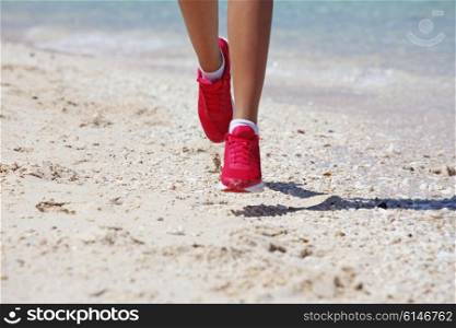 Woman jogging on beach . Close-up view of Running woman feet jogging on beach