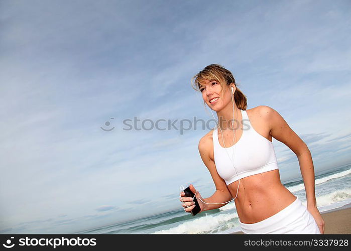 Woman jogging on the beach with music player