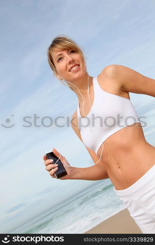 Woman jogging on the beach with music player