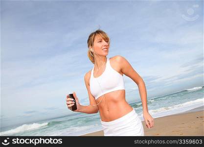 Woman jogging on the beach with music player