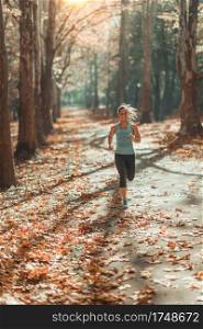 Woman Jogging Outdoors In Autumn in Public Park