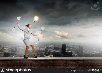 Woman juggler. Young pretty businesswoman juggling with light bulbs