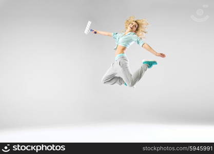 Woman jumping and holding a paintroller