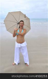 woman jumping on a tropical beach holding an umbrella