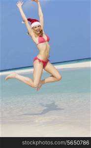 Woman Jumping On Beach Wearing Santa Hat