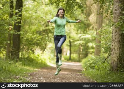 Woman jumping on path smiling