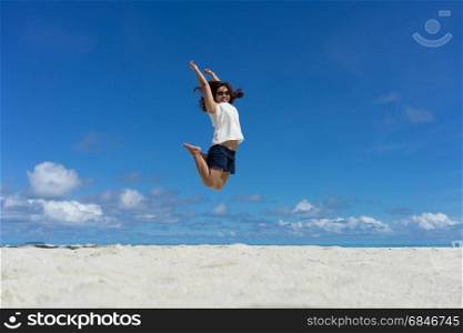 Woman jumping on the sand of the beach