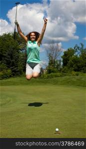 Woman jumps for joy as the ball heads into the cup on the golf green