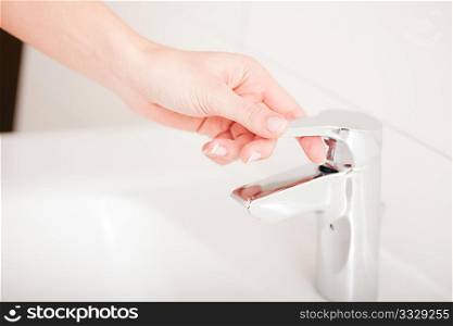 Woman (just hand to be seen) closing the water tap after washing her hands