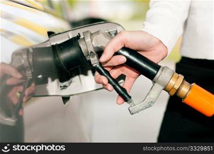 Woman - just hand to be seen - refueling her car with LPG gas at a station