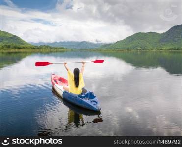 Woman kayaking on lake and mountain in Thailand