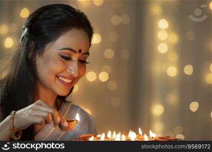 Woman keeping a diya in the plate on the occasion of Diwali