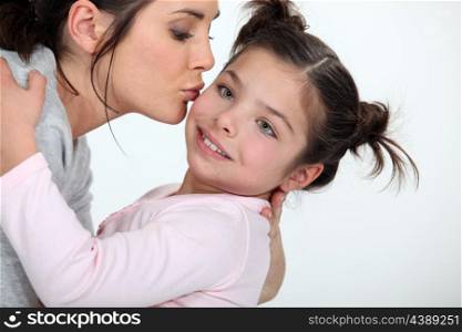 Woman kissing cute little girl