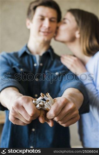 woman kissing her boyfriend broken bundle cigarettes