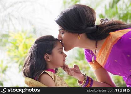 Woman kissing her daughters forehead