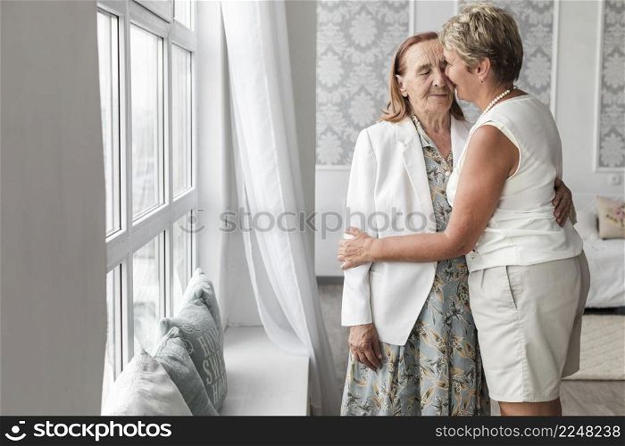 woman kissing her senior mother home
