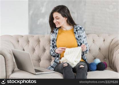 woman knitting looking laptop