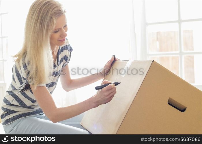 Woman labeling moving box at home