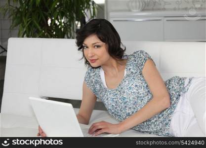 Woman laid in couch with laptop