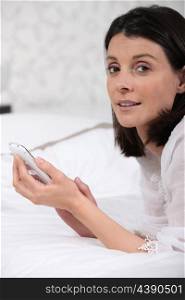 Woman laid on a bed sending text message