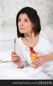 Woman laid on her bed eating dessert