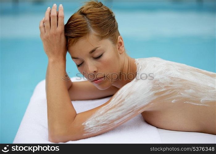 Woman laid on massage table with cream on her back