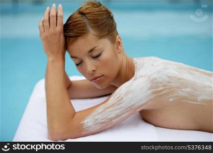 Woman laid on massage table with cream on her back