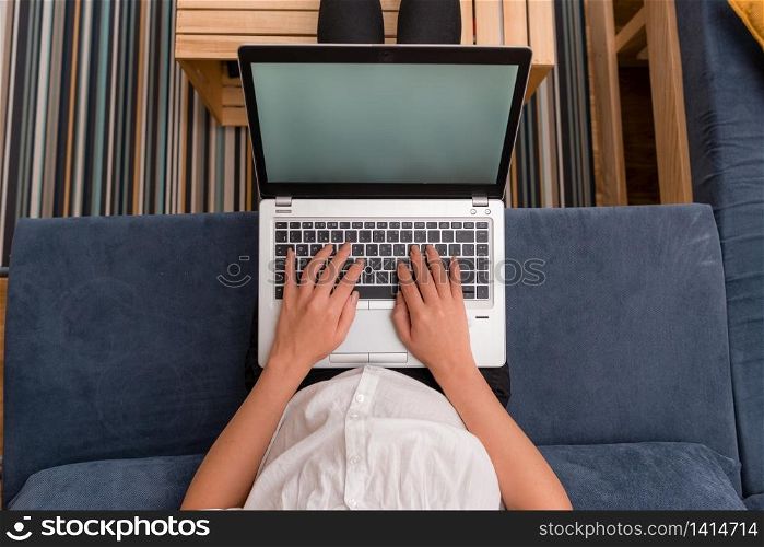 woman laptop computer office supplies technological devices inside home. Young lady using a gray laptop computer and typing in the black keyboard with both hands in a room. Woman in a house ambient with office supplies and technological devices.