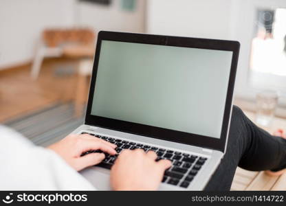 woman laptop computer office supplies technological devices inside home. Young lady using a gray laptop computer and typing in the black keyboard with both hands in a room. Woman in a house ambient with office supplies and technological devices.