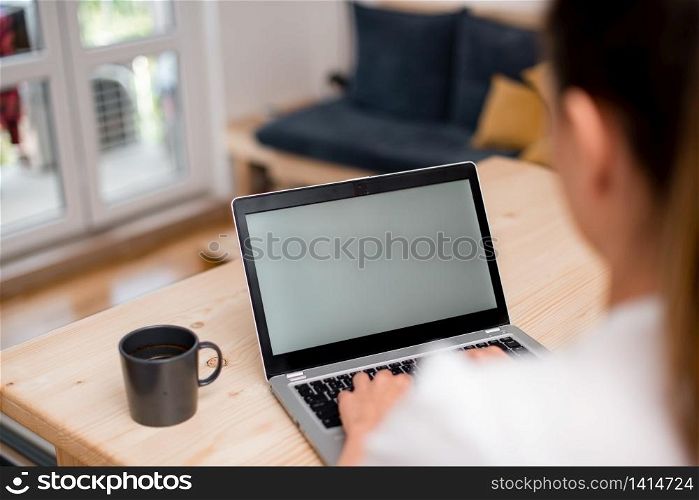 woman laptop computer office supplies technological devices inside home. Young lady using a gray laptop computer and typing in the black keyboard with both hands in a room. Woman in a house ambient with office supplies and technological devices.