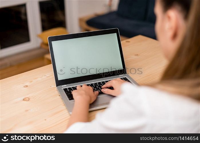 woman laptop computer smartphone mug office supplies technological devices. Young lady using a gray laptop computer and typing in the black keyboard with both hands in a living room. Office supplies, technological devices and wooden desk.