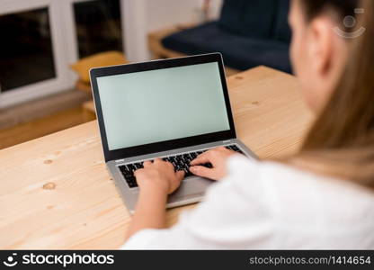 woman laptop computer smartphone mug office supplies technological devices. Young lady using a gray laptop computer and typing in the black keyboard with both hands in a living room. Office supplies, technological devices and wooden desk.