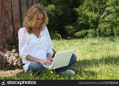 Woman laughing at her laptop computer in the park