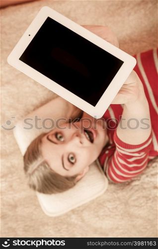 Woman laying and holding tablet computer with blank screen showing copyspace. Happy smiling woman advertising new modern technology.. Woman holding pc tablet. Blank screen copyspace