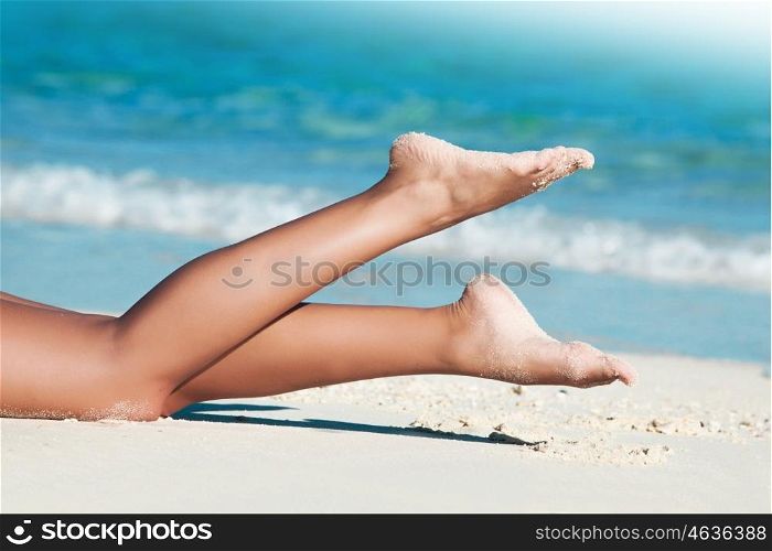Woman laying by sea. Legs of young woman laying by tropical sea
